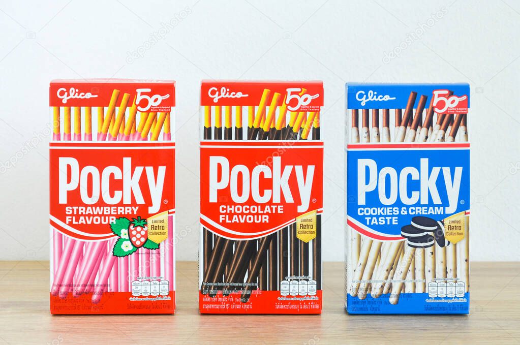 Phuket, Thailand -  November 12, 2020 : Packaging box of Glico brand Pocky biscuit sticks strawberry, chocolate and cookie and cream flavor (limited retro collection) on wooden table with white background