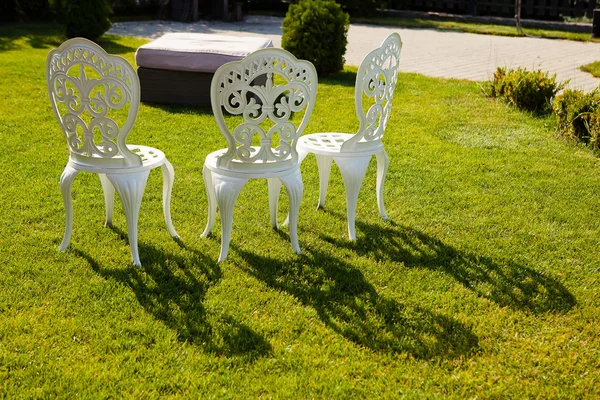 Cadeiras brancas esculpidas no gramado no pátio Imagem De Stock