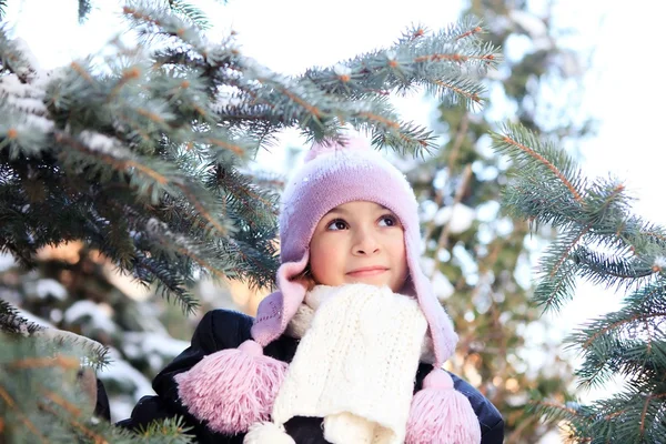 Cheerful beautiful girl in purple winter hat in the snow under the Christmas tree — Stock Photo, Image