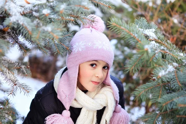 Cheerful beautiful girl in purple winter hat in the snow under the Christmas tree — Stock Photo, Image