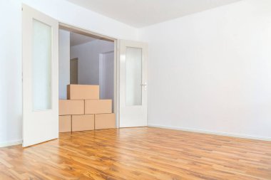 Boş bir dairede beyaz bir duvara karşı kutuları taşımak.