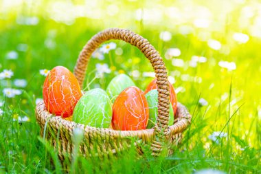 Çayırdaki sepette bir sürü renkli paskalya yumurtası var.