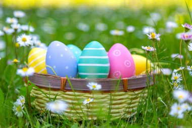 Çayırdaki sepette bir sürü renkli paskalya yumurtası var.