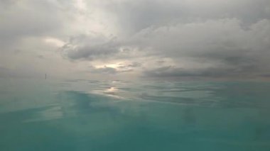 Suyun yüzeyinde bir sürü bulutlu mavi gökyüzü ile yüzmek.