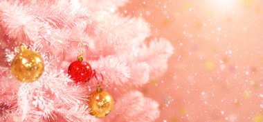 Bulanık pembe bir arkaplanda Bokeh ile noel baloları olan bir Noel ağacının beyaz dalları.