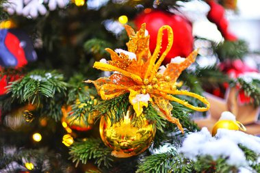 Noel ağacı süslemeleri. Noel ağacındaki altın bir çiçek. Yılbaşı ışıklarının ve bokeh 'in arka planında. Noel arkaplanı