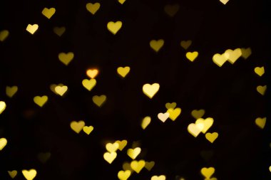 Bir düğün kartı ya da Sevgililer Günü için siyah bir arka planda sarı kalplerle soyut bulanıklık