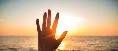 El, günbatımının arka planında. Güneş ışınları ve parıldıyor