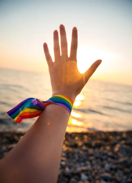 Hand Med Regnbågsband Symbol För Hbt Bakgrunden Havssolnedgång Genom Solens — Stockfoto