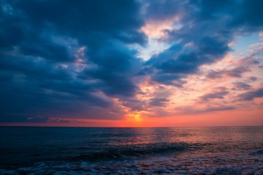 Bulutlu, denizin üzerinde renkli bir gün batımı. Doğal arkaplan