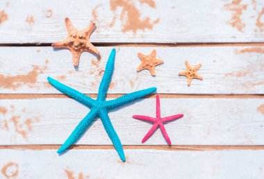 Tahta beyaz arka planda güzel deniz yıldızları. Yaz arkaplanı, üst görünüm