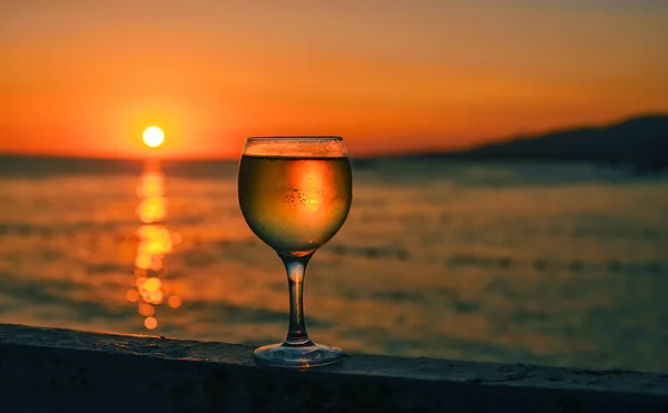 在大海的夕阳西下 一杯白葡萄酒在水面上闪烁着美丽的光芒 — 图库照片
