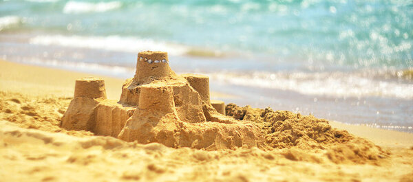 Sand castle on the sandy shore against the background of the sea. summer landscape