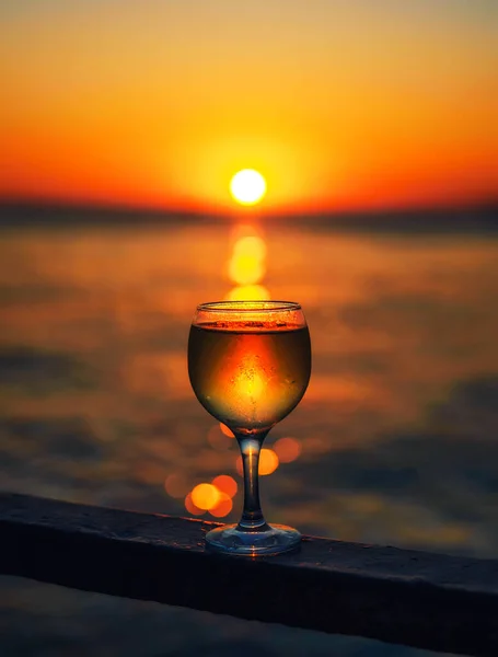 一杯白葡萄酒 夕阳西下 太阳落在海滩上 阳光照在玻璃杯里 — 图库照片