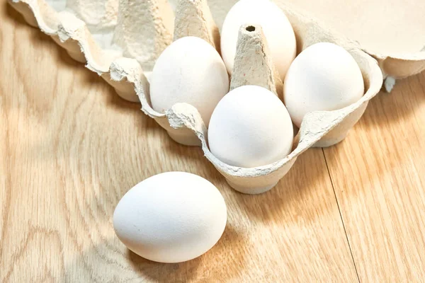 Сырые куриные яйца в картонной коробке на столе. — стоковое фото