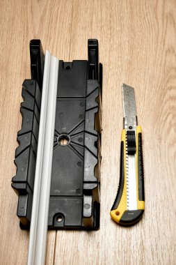 Köşe budama kutusu kullanarak yazman bıçağıyla köpüklü etek tahtasını kes. Tadilat işi. Apartmanda tamirat var. Genişletilmiş polistiren panel