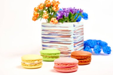 Tatlı badem kurabiyeli kompozisyon ve beyaz arka planda çiçekli vazo.