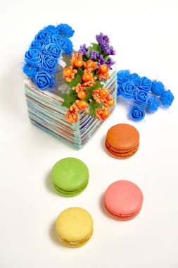 Tatlı badem kurabiyeli kompozisyon ve beyaz arka planda çiçekli vazo.