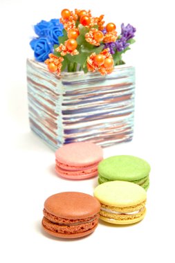 Tatlı badem kurabiyeli kompozisyon ve beyaz arka planda çiçekli vazo.