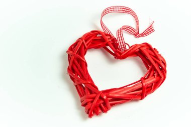 Beyaz arka planda el yapımı ağaç dallarından yapılmış kırmızı hasır kalp. Aşk tatili. Sevgililer Günü