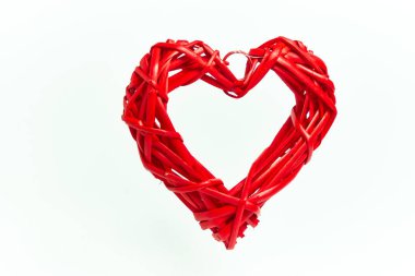 Beyaz arka planda el yapımı ağaç dallarından yapılmış kırmızı hasır kalp. Aşk tatili. Sevgililer Günü