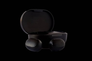 Kablosuz kulaklıklar siyah arkaplanda izole edilmiş. Yakın plan. Suçlama davasında kulaklık.