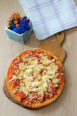 Maya hamurundan yapılan iştah açıcı ev yapımı pizza, tahtadan yapılma bir tahtanın üzerinde yemeye hazır.