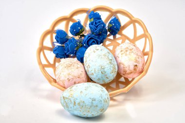 Çiçeklerle boyanmış Paskalya yumurtaları hasır bir tabakta yatıyor.