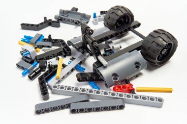 Yapıcının plastik parçaları, hareket edebilen modelleri beyaz arka planda birleştirmek için elementleri ve tekerlekleri bağlayan, yüzen odaklı