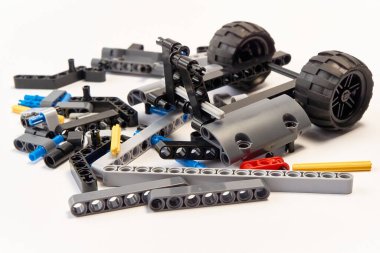 Yapıcının plastik parçaları, hareket edebilen modelleri beyaz arka planda birleştirmek için elementleri ve tekerlekleri bağlayan, yüzen odaklı