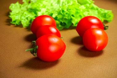 Kırmızı kiraz domatesleri marul yaprağının üzerinde yatıyor..