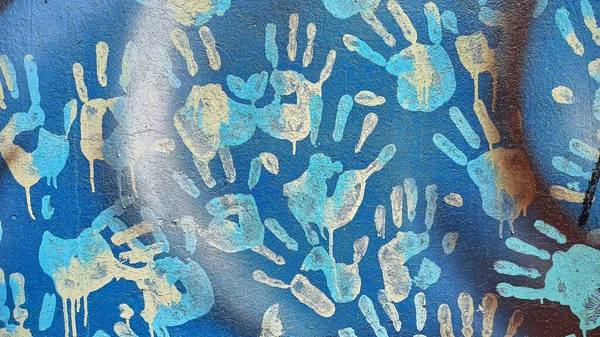 Handprints and dripping paint on the textured background of an old painted wall