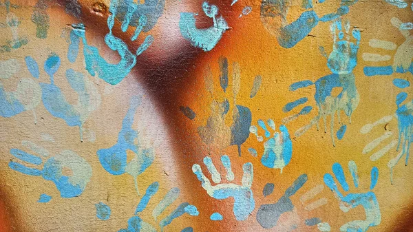 Handprints and dripping paint on the textured background of an old painted wall