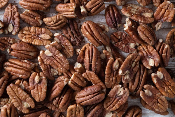 Ovanifrån av skalade bruna pekannötter som liknar valnötter. Begreppet hälsosamt mellanmål. Real storlek pekan bakgrund — Stockfoto