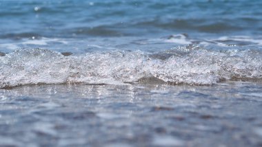 Küçük deniz dalgalarının seçici odak noktası. Parlak açık mavi ve beyaz dalga. Deniz meditasyonunun duvar kağıdı. Dinlen, sakinleş.