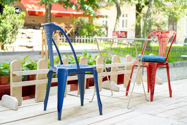 Restaurant en plein air. Chaises rouges et bleues et table blanche au café. Café plein air vide été à la ville européenne — Photo