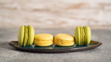 Şam fıstığı ve mango kremalı sarı ve yeşil badem kurabiyesi. Renkli kekleri kremayla doldurmak.