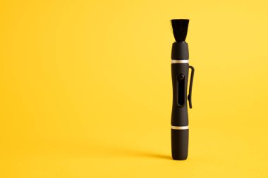 Sarı arka planda siyah lens temizleme kalemi. Mercek temizleme fırçası. Temizlik optikleri için fırça izole edildi