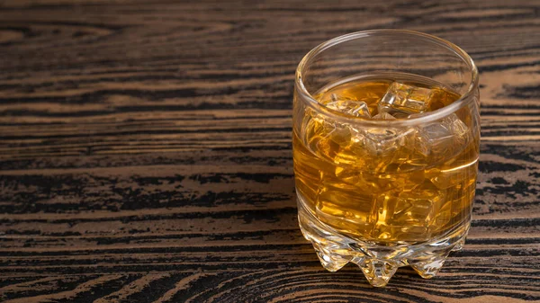 Copo de uísque escocês e gelo na mesa de madeira.Um copo de licor duro. Feche o uísque em um copo de vidro — Fotografia de Stock