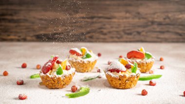 Üzerinde muz dolgusu ve meyve olan dört yulaf ezmesi sepeti. Pudra şekeri keklerin üzerine düşer. Metin için boşluk