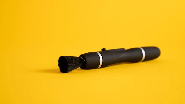 Lens pen and brush for cleaning camera isolated on yellow background. The black lenspen. — Stock Photo, Image
