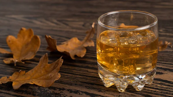 Copo de uísque escocês e folhas secas. Alcoolismo de outono. Brandy e folhas de carvalho secas — Fotografia de Stock