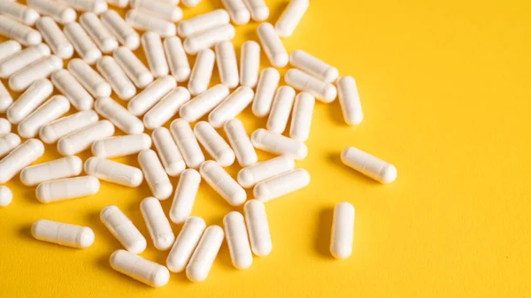Sarı arka planda izole edilmiş bir magnezyum takviye kapsülü yığını. Yiyecek takviyesi. D3 vitamini