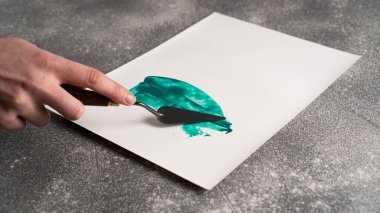 Standart palet bıçağını tutarak ve beyaz kağıda soyutlama resmi yaparak. Palet bıçağını bırak
