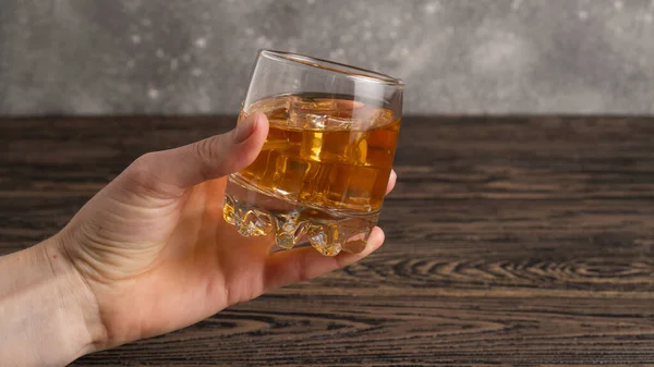 Glass of brown rum in hand. Hand hold mug of bourbon. Glass of scotch whiskey and ice — Stock Photo, Image