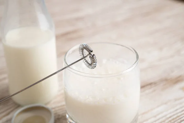 Milk frother and glass of milk. Glass bottle. Milk bubbles