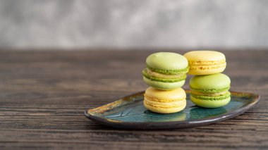 Ahşap masa üzerinde yazı alanı olan güzel bir yaprak tabaktaki canlı yeşil ve sarı badem kurabiyeleri.