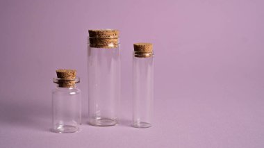 Mantarlı küçük dekoratif kavanozlar. Mor arkaplandaki boş şişe kolyesinin çeşitleri. Ağaç minik cam şişeler.