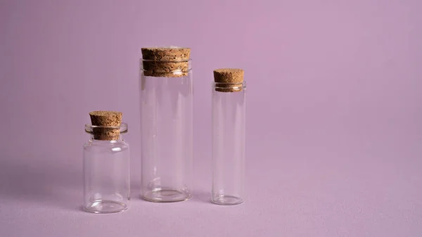 Pequeños frascos decorativos con corcho. Variaciones de collar vial vacío sobre fondo púrpura. Árbol diminutas botellas de vidrio —  Fotos de Stock