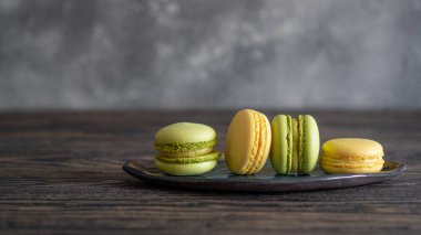 Tahta zemin üzerinde metin alanı olan canlı yeşil ve sarı badem kurabiyeleri.